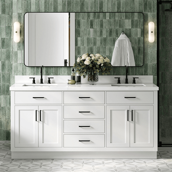 White double sink bathroom vanity White double sink vanity with silver hardware, marble top, and twin mirrors against a green tiled wall.